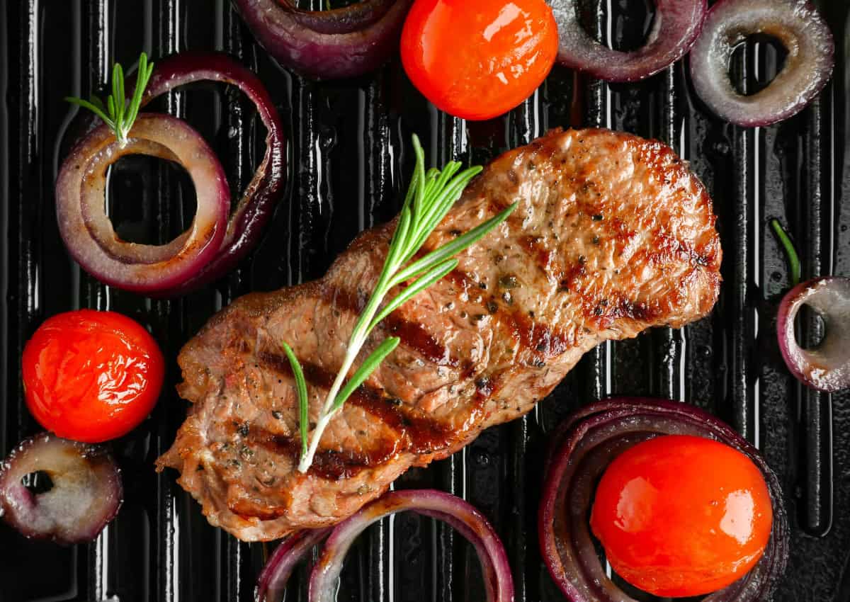Grilled flank steak with red onions, tomatoes and fresh sprig of rosemary.