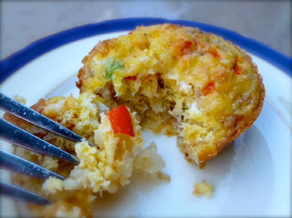 Individual frittata baked in muffin tin on blue rimmed white plate with fork digging into it
