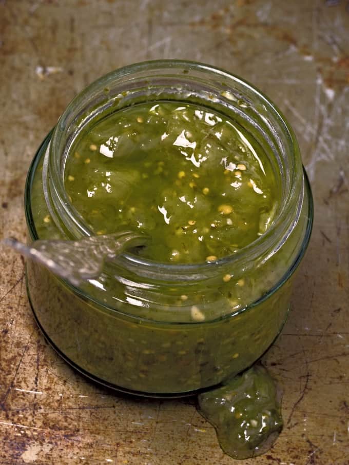Green salsa verde in glass jar with spoon.