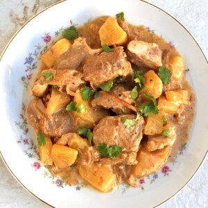 shallow bowl of crockpot pineapple pork garnished with chopped parsley shot from above