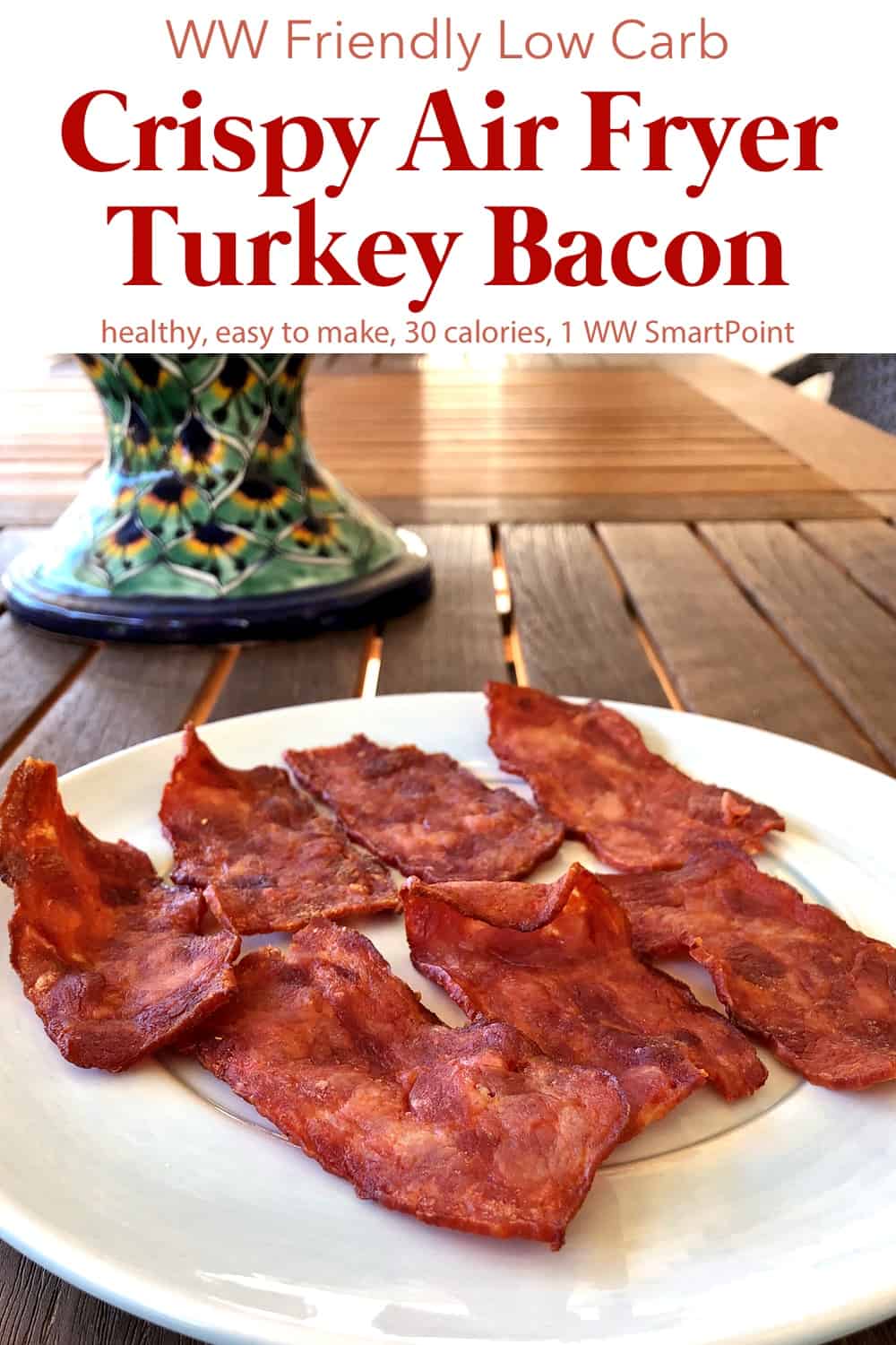 Crispy air fryer turkey bacon on a plate on wooden table.