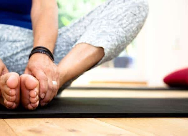 Woman seated on floor stretching hips