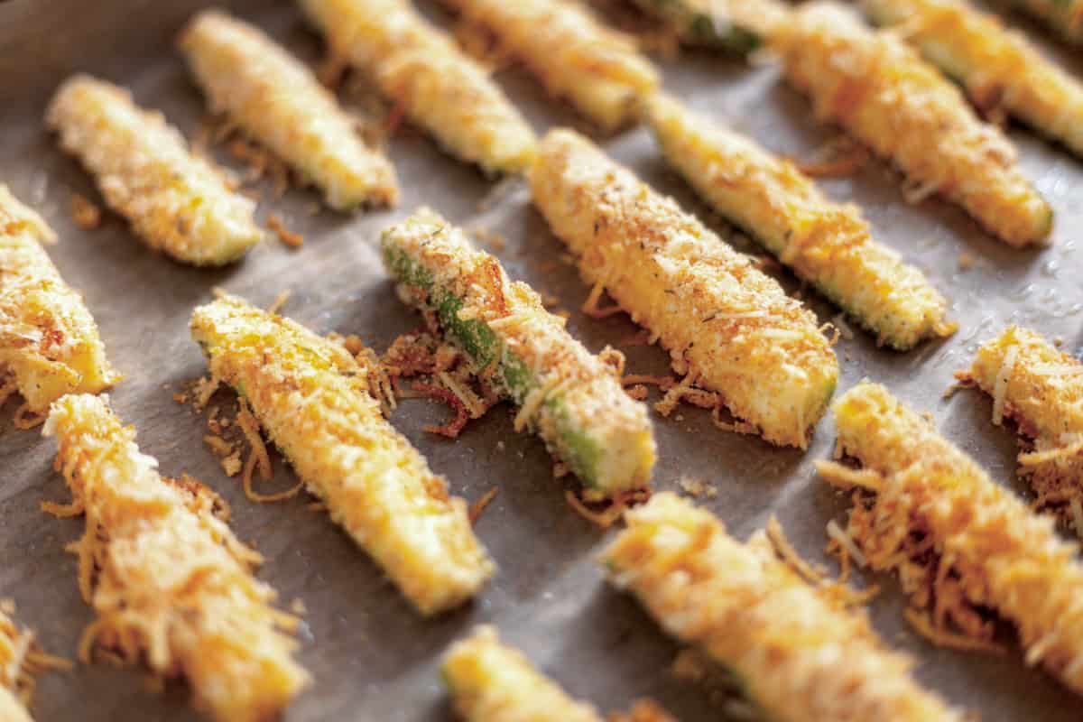 Fresh baked crispy zucchini fries on parchment paper.
