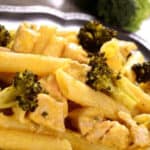 Close up of penne pasta with chicken and broccoli on dinner plate.