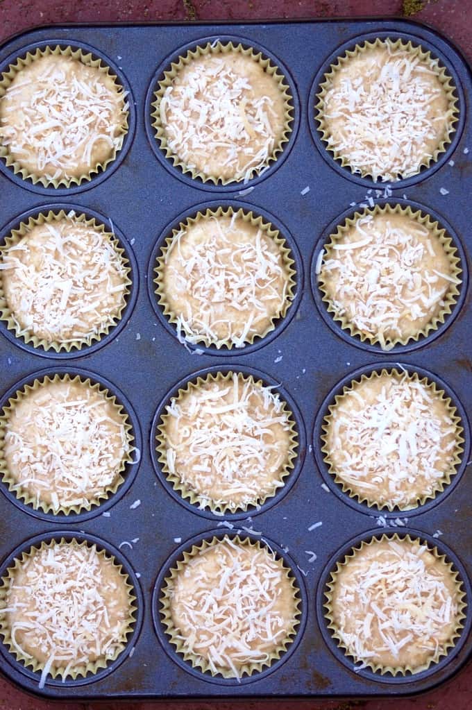 Uncooked coconut muffins topped with shredded coconut in muffin pan.