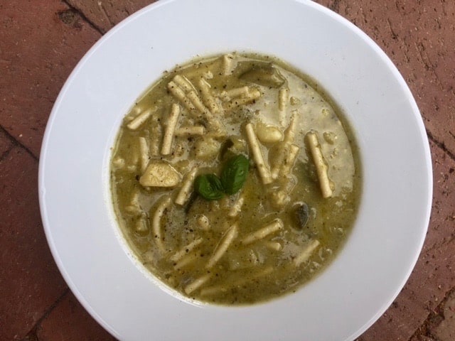 Italian Zucchini Pesto Soup in white bowl garnished with fresh basil.