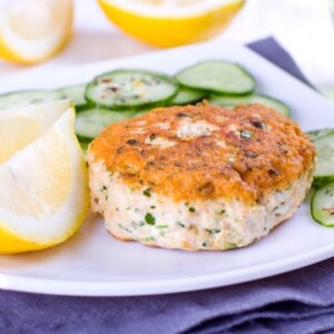 Close up of a salmon cake served with cucumber and lemon
