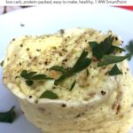 Microwave mug frittata on plate sprinkled with salt, pepper and fresh herbs