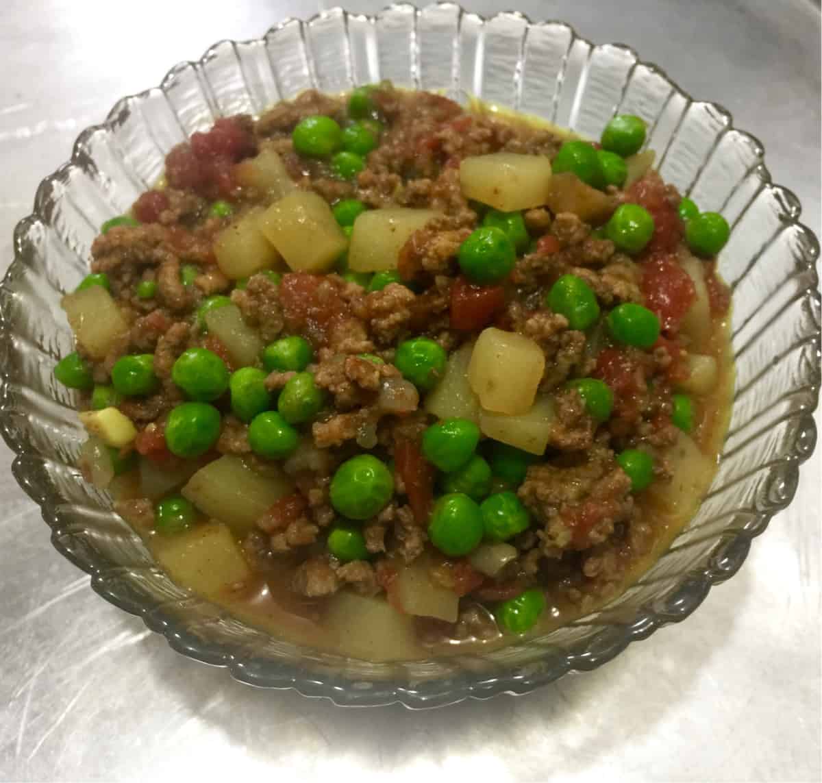 Hamburger Curry with potatoes and peas in glass bowl.