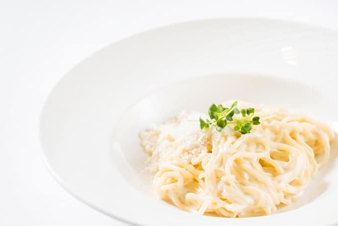 pasta with cheese in a white bowl with herb garnish