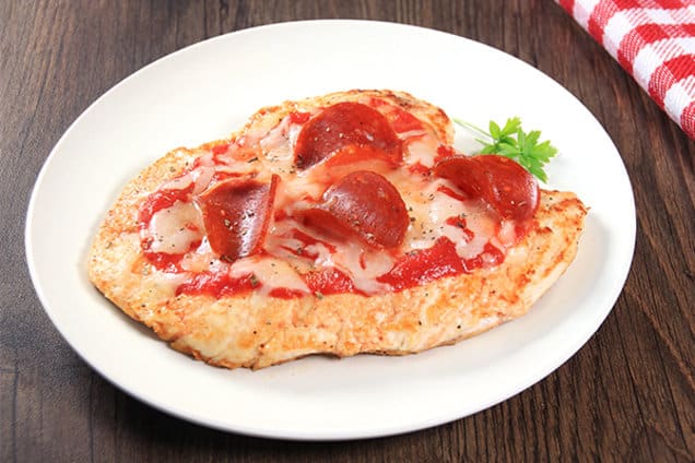 chicken breast topped with pizza sauce, mozzarella and pepperoni on white plate