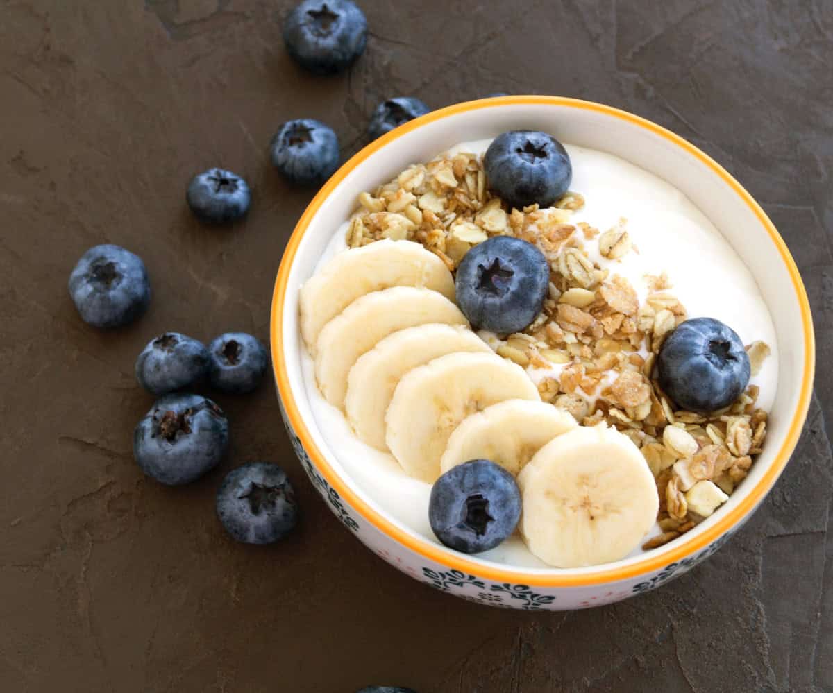 Muesli and yogurt in a bowl with fresh blueberries and banana slices.