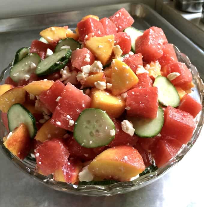 Watermelon Peach Salad with cucumbers and Feta cheese in a crystal bowl.
