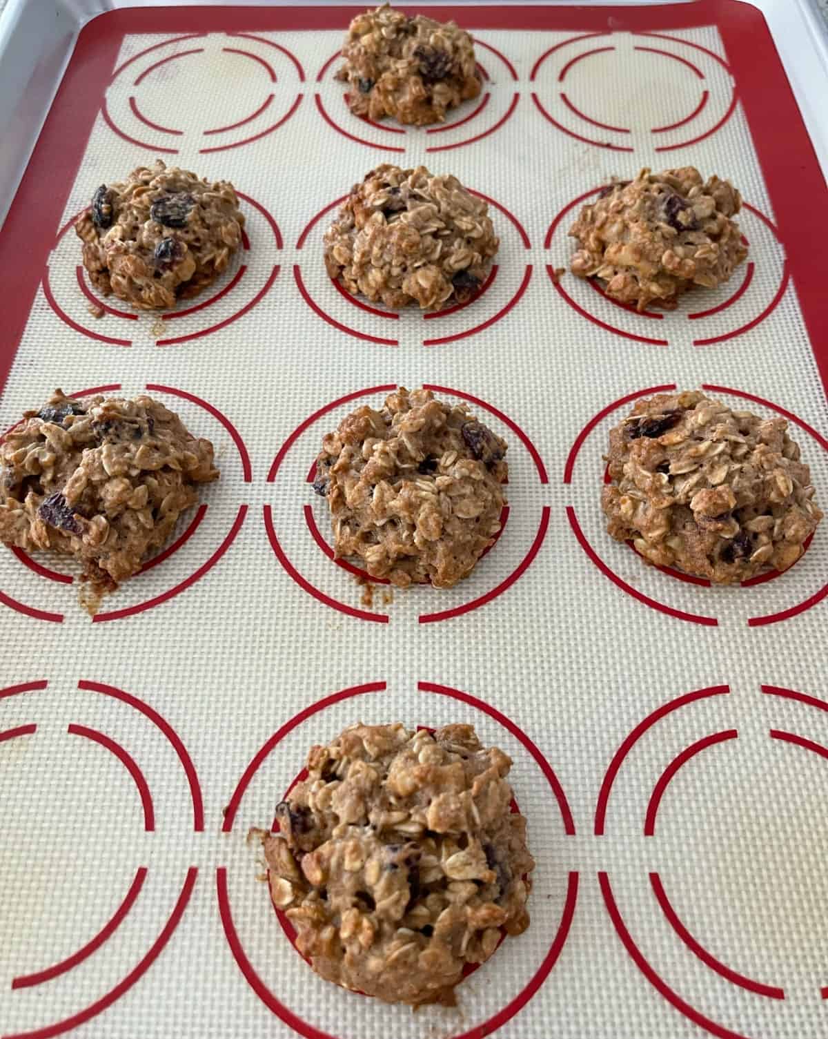 Fresh baked applesauce oatmeal cookies on silicone mat lined baking sheet.