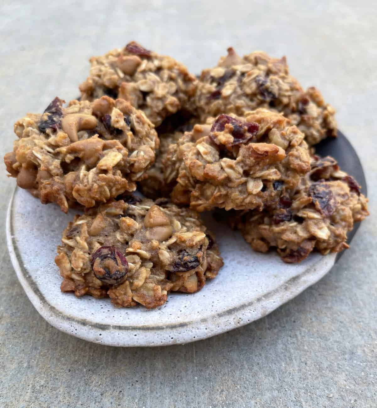 Applesauce Oatmeal cookies with dried cranberries stacked on ceramic plate.