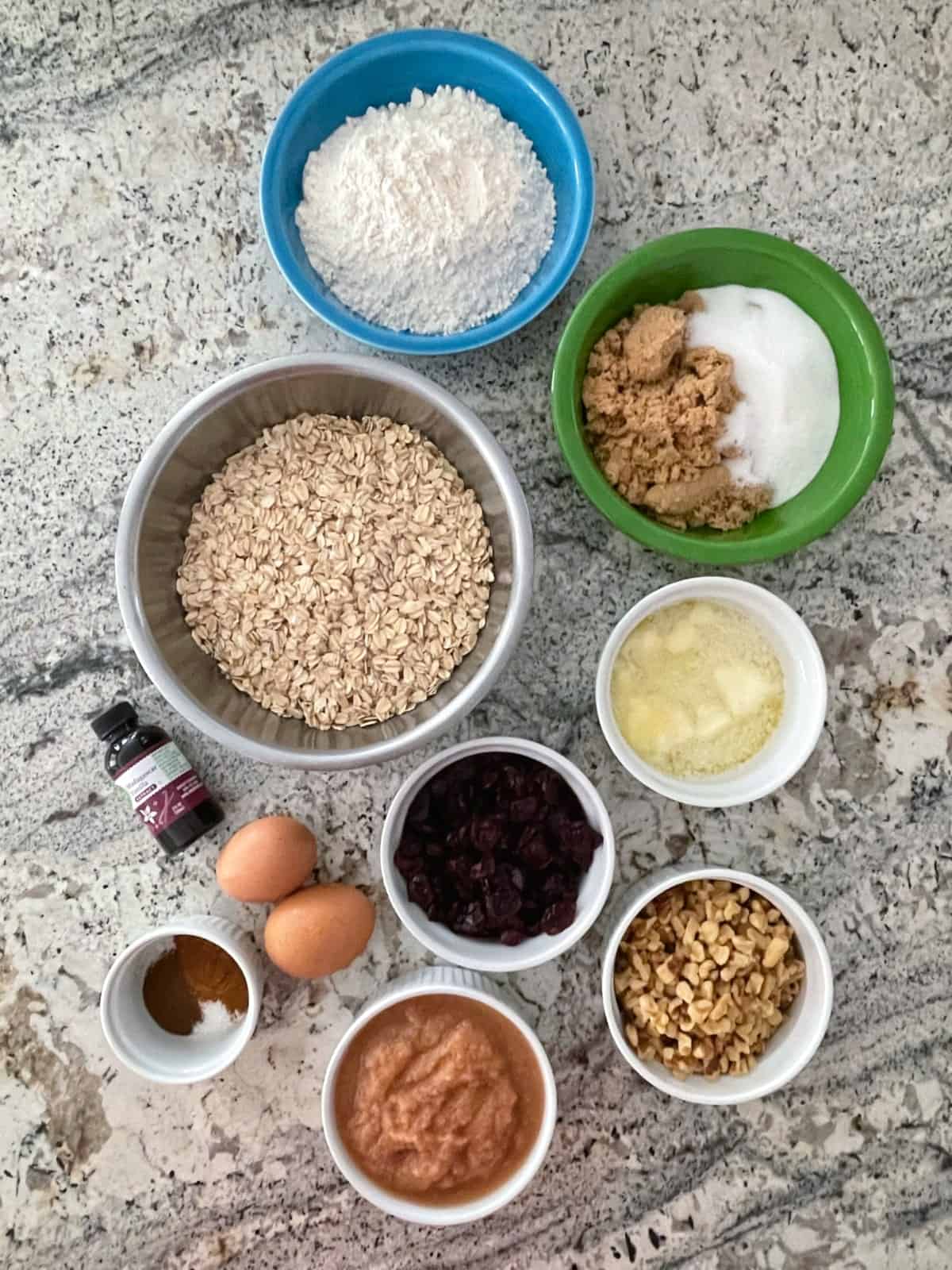 Ingredients including rolled oats, all-purpose flour, brown sugar, sugar, melted butter, dried cranberries, walnuts, cinnamon applesauce, two eggs and vanilla.