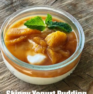 Skinny Greek yogurt pudding with cardamom and oranges topped with fresh mint in small glass dessert bowl on wooden table.
