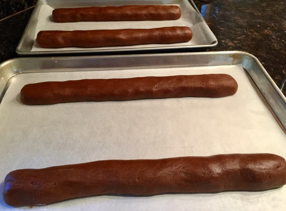 4 logs of molasses cookie dough on 2 parchment lined cookie sheets.