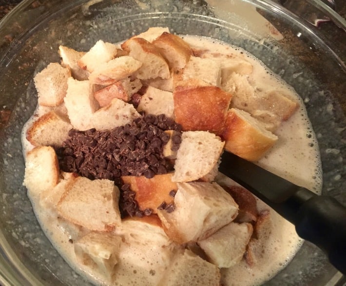 Making chocolate banana bread pudding with cubed bread and chocolate chips.
