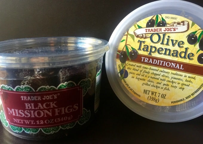 A container of fresh black mission figs near a container of olive tapenade.