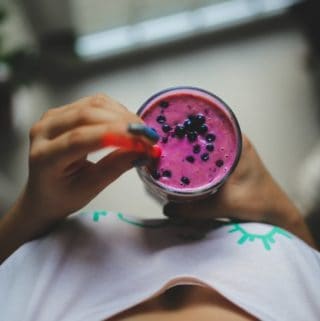 woman holding blueberry smoothie shot from above