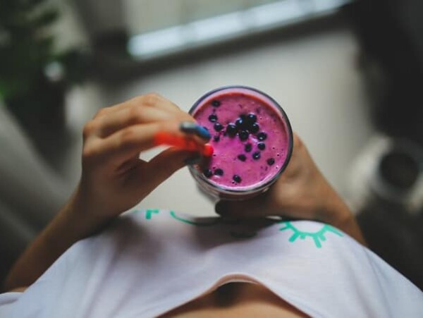 woman holding blueberry smoothie shot from above