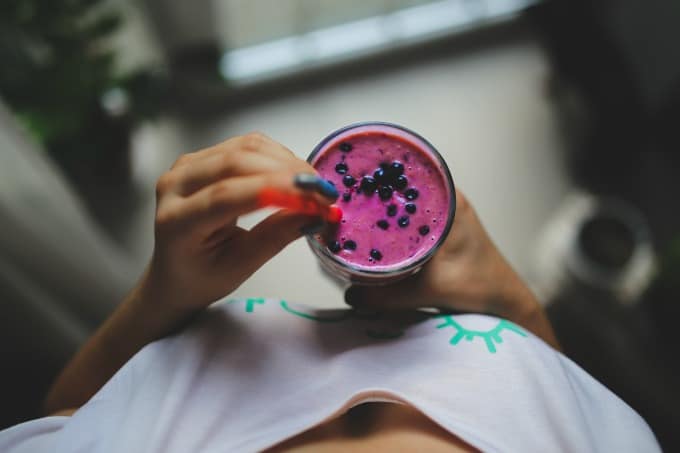 woman holding blueberry smoothie shot from above