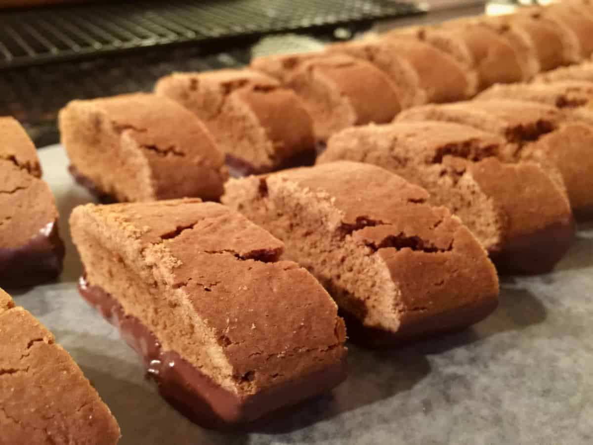 2 rows of chocolate dipped gingerbread cookie slices on parchment paper.