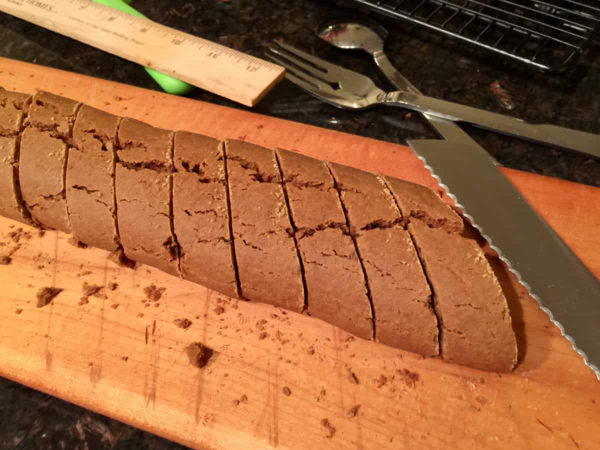 Sliced molasses cookies on a cutting board with serrated knife alongside.
