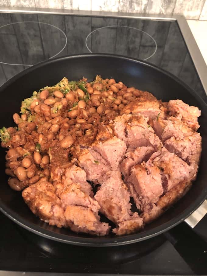 Skillet on stove with ground turkey, pinto beans, shredded zucchini and taco simmer sauce