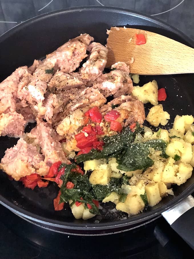 Cooking turkey sausage, red bell pepper, spinach and potatoes in a skillet