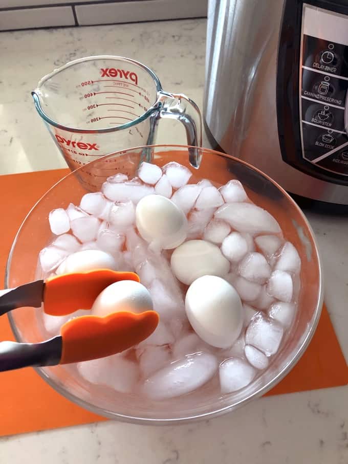 Placing hard boiled eggs into ice water bath with tongs