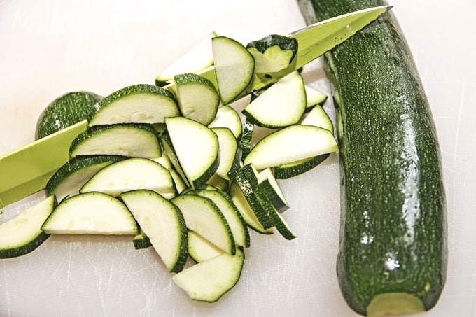 Slices of a zucchini squash with knife and zucchini