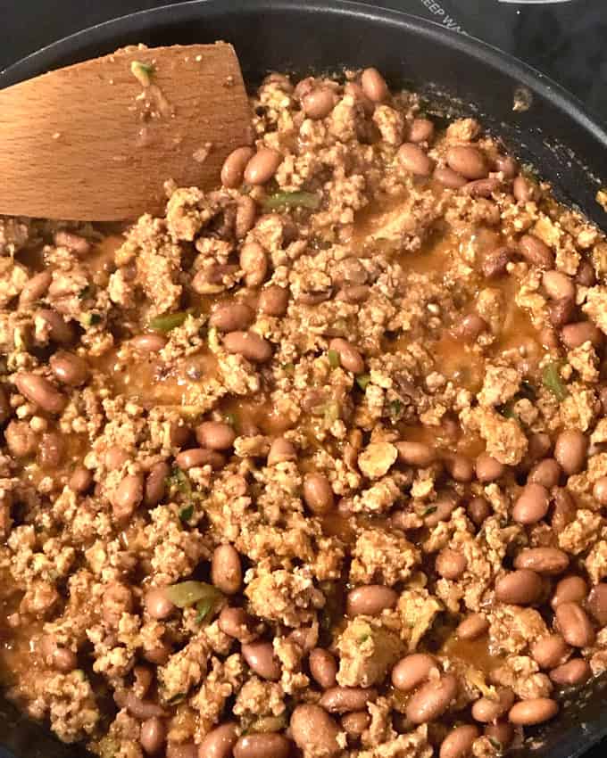 Skillet with cooked ground turkey, pinto beans, jalapeño pepper and taco simmer sauce