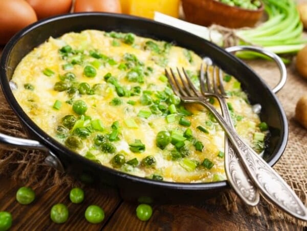 tortilla pan filled with pea omelet with forks arranged atop