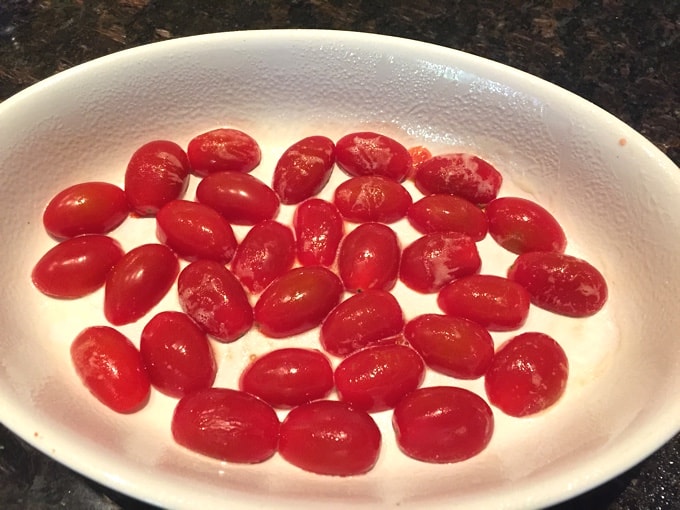 Cherry tomatoes sliced in half in baking dish