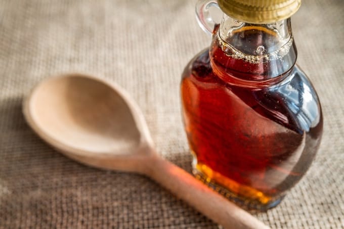 Small bottle of maple syrup with a wooden spoon