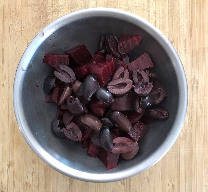 Chopped red beets with Mediterranean black olives in mixing bowl.