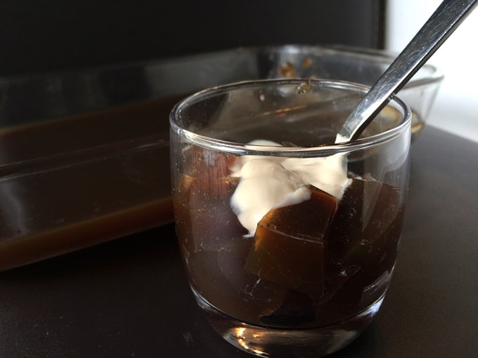 Coffee jello in dessert glass with whipped cream and spoon.