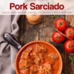 Filipino Pork Sarciado Stew in a pot on wooden table with fresh tomatoes