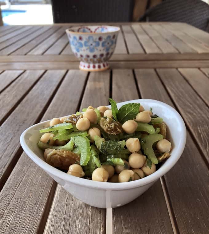 Vegetarian chickpea salad with raisins and mint in small white bowl.