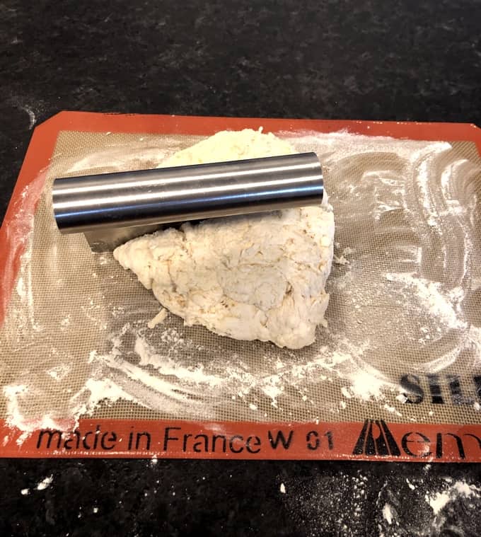 Cutting scone dough in half on floured baking mat