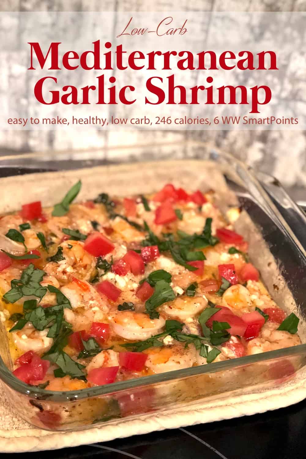 Glass baking dish with garlic shrimp garnished with chopped tomato, parsley and feta cheese.