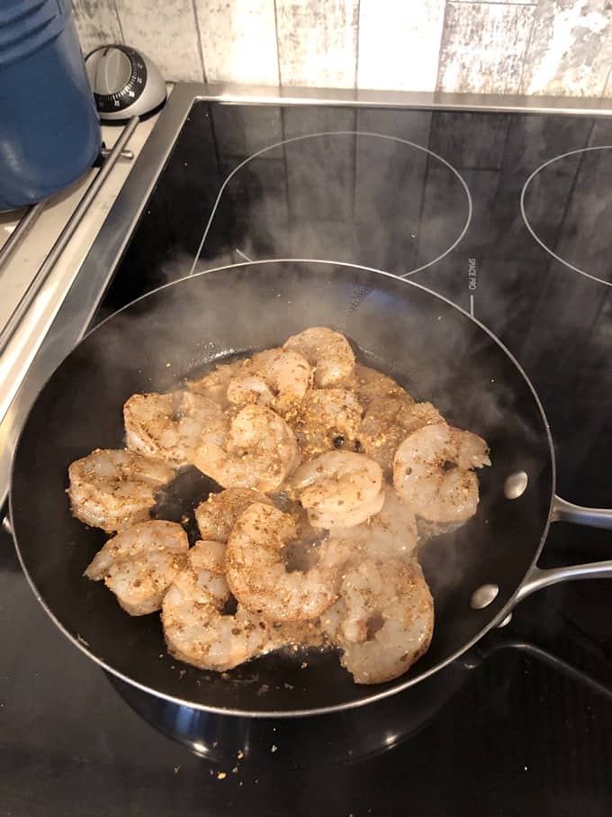 Sautéing spiced shrimp in pan on stove
