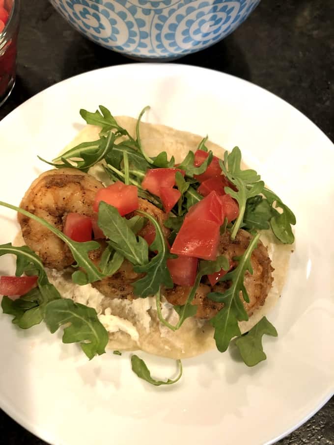 Spice-Rubbed Soft Shrimp Taco topped with tomatoes and arugula on plate