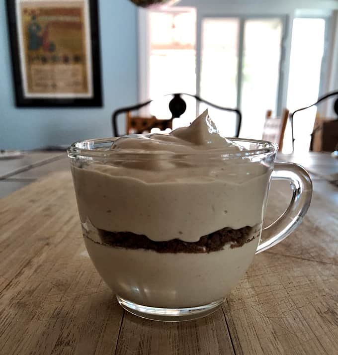 Layered whipped peanut butter yogurt with crushed chocolate graham crackers in dessert glass.