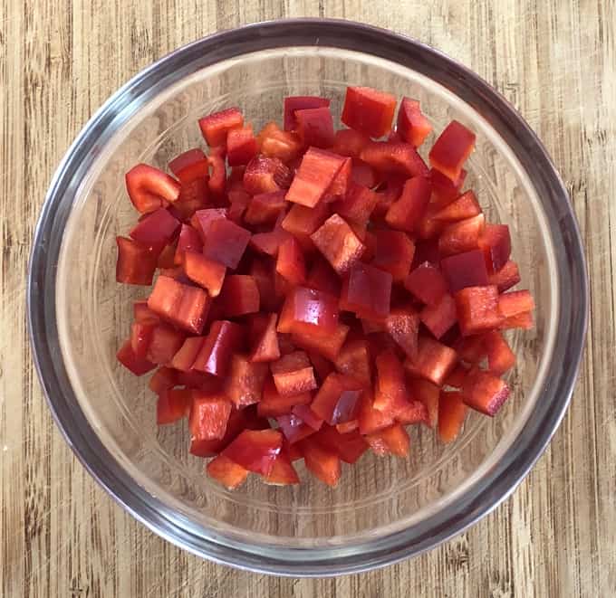 Chopped red bell pepper in glass bowl.