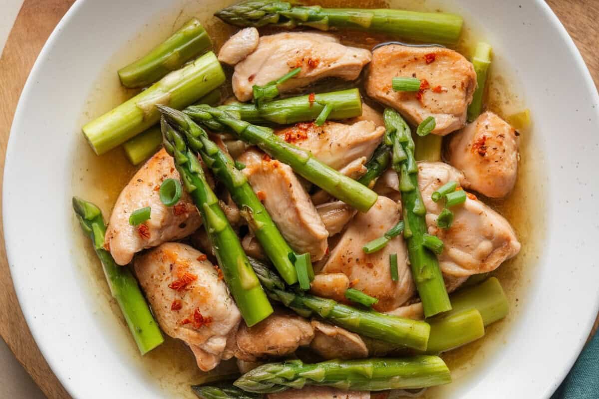chicken and asparagus stir fry in shallow rimmed white dish from above