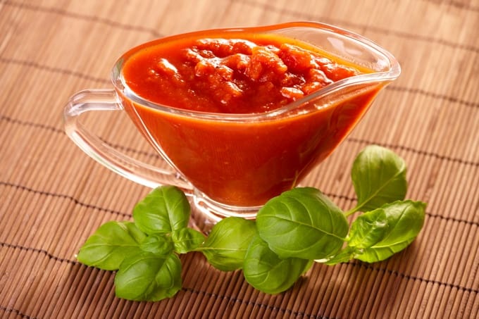 Fresh tomato sauce in glass dish with fresh basil leaves.