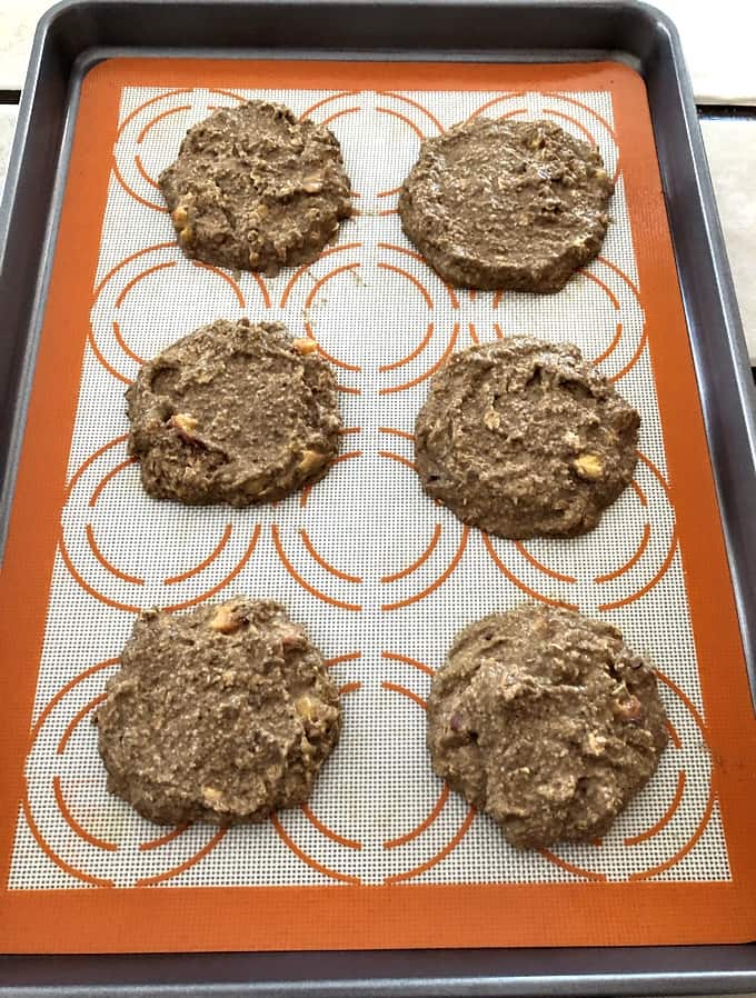 Six mounds of peach cookie batter on baking sheet with silicone mat